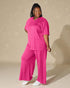 Woman wearing a bright pink outfit against a beige background