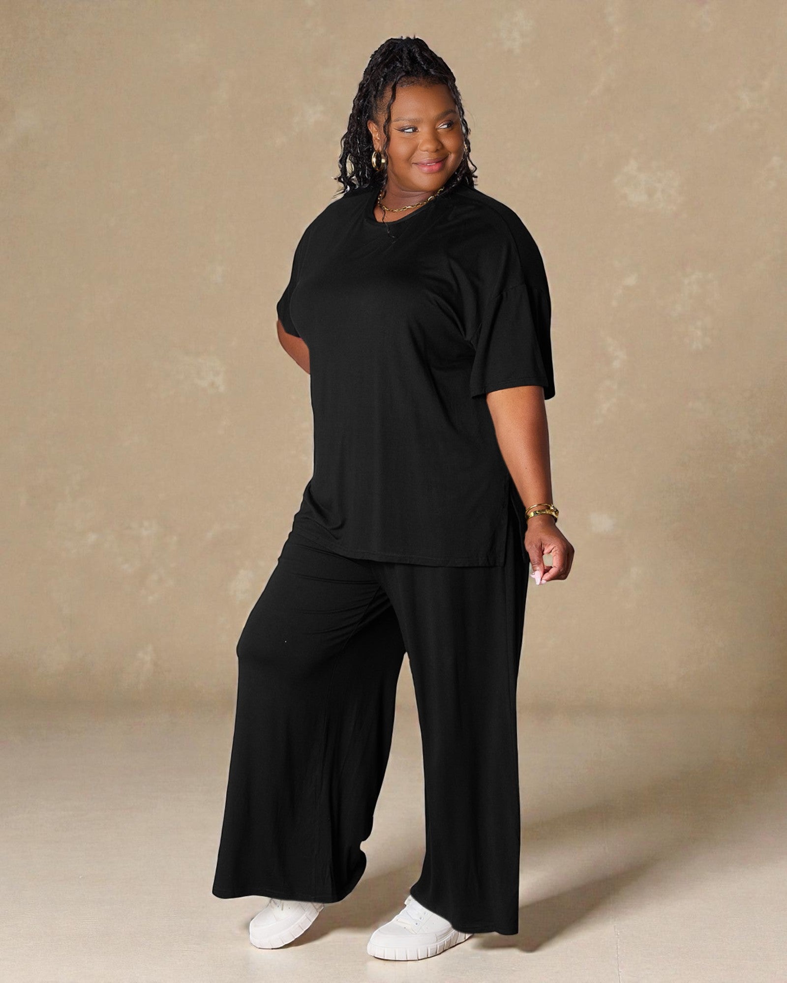 Person wearing a black outfit against a beige background