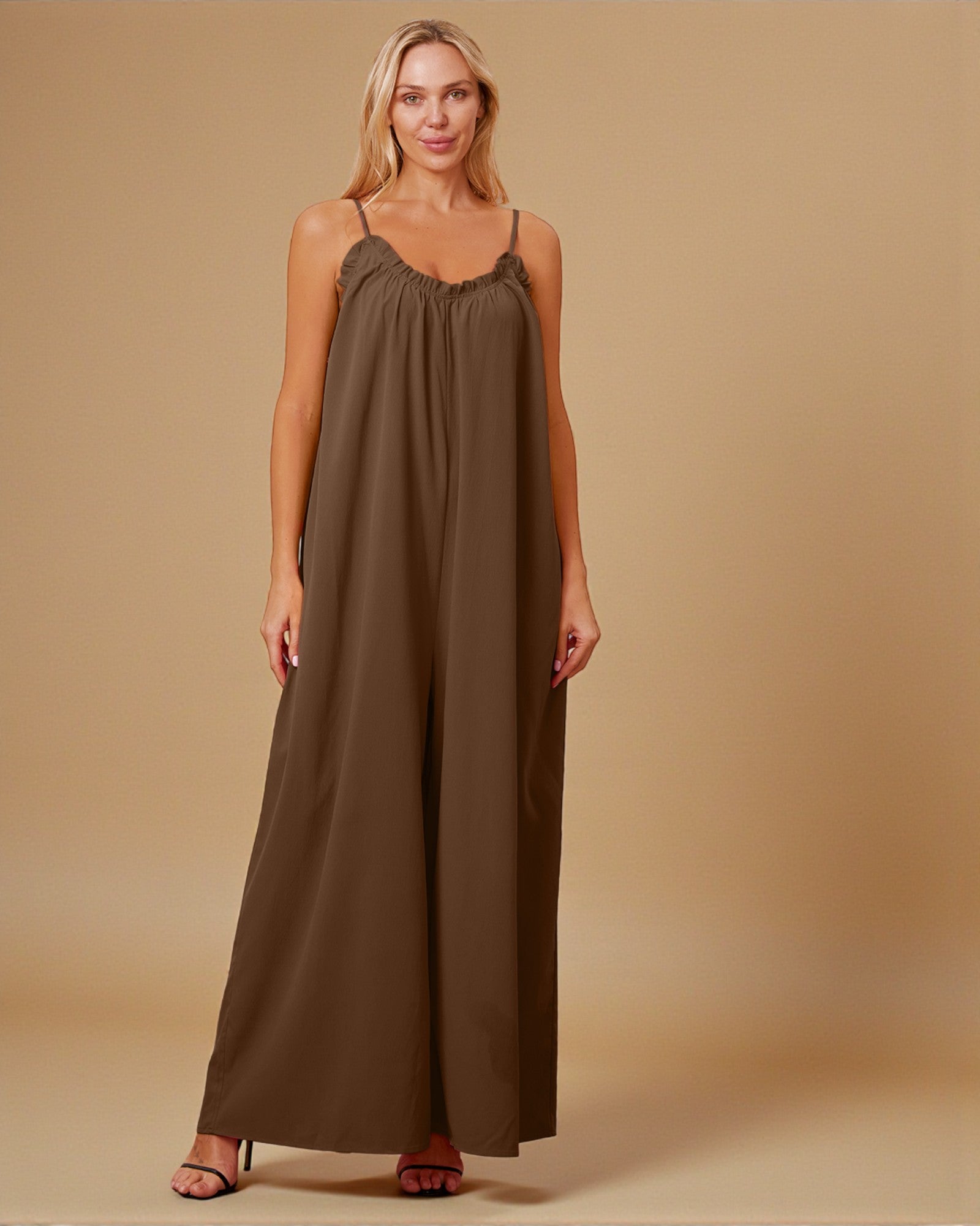 Woman wearing a brown jumpsuit against a beige background