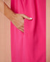 Hand with white nail polish on a bright pink fabric background