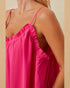 Close-up of a person wearing a bright pink dress with thin straps against a beige background