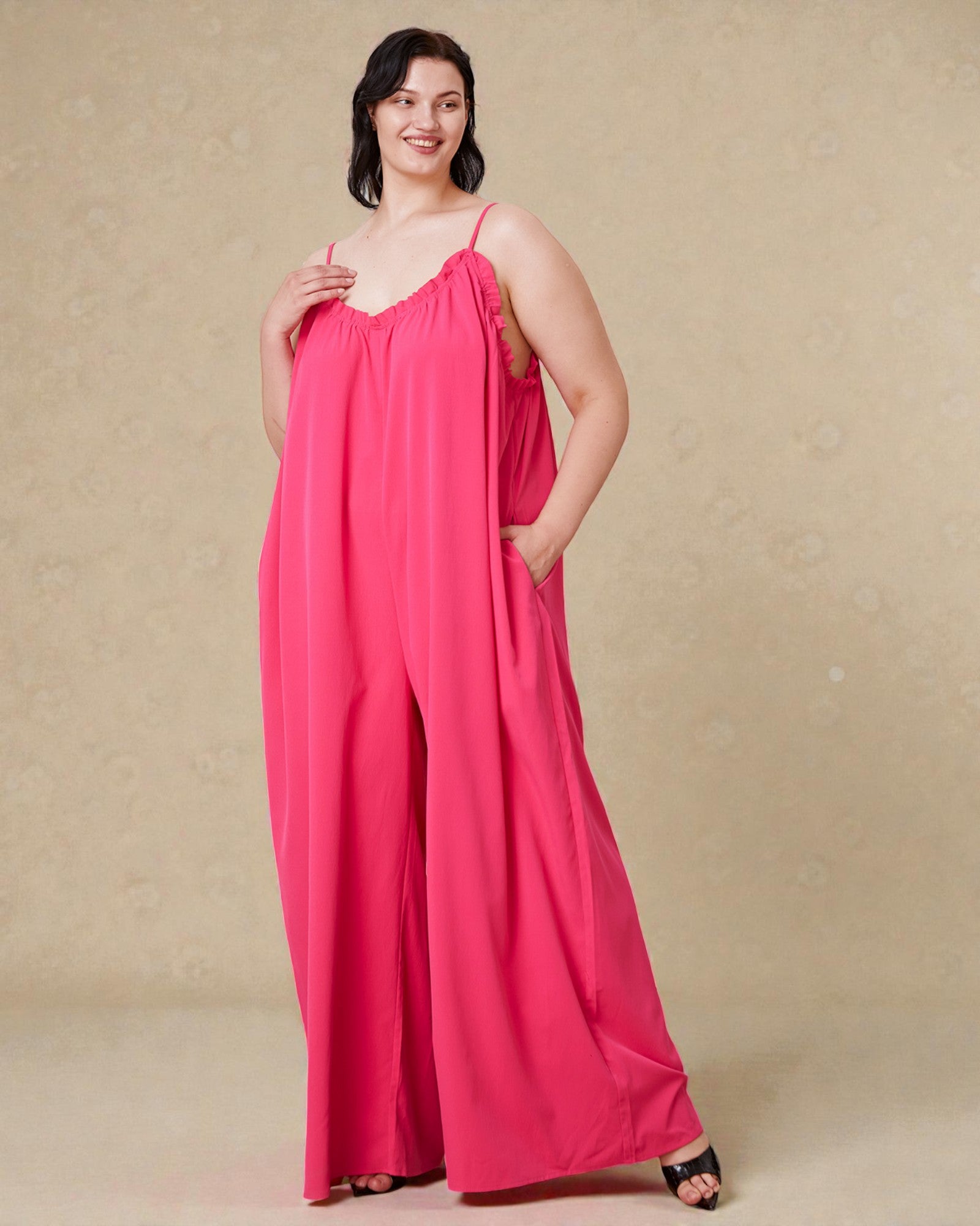 Woman wearing a pink jumpsuit against a beige background