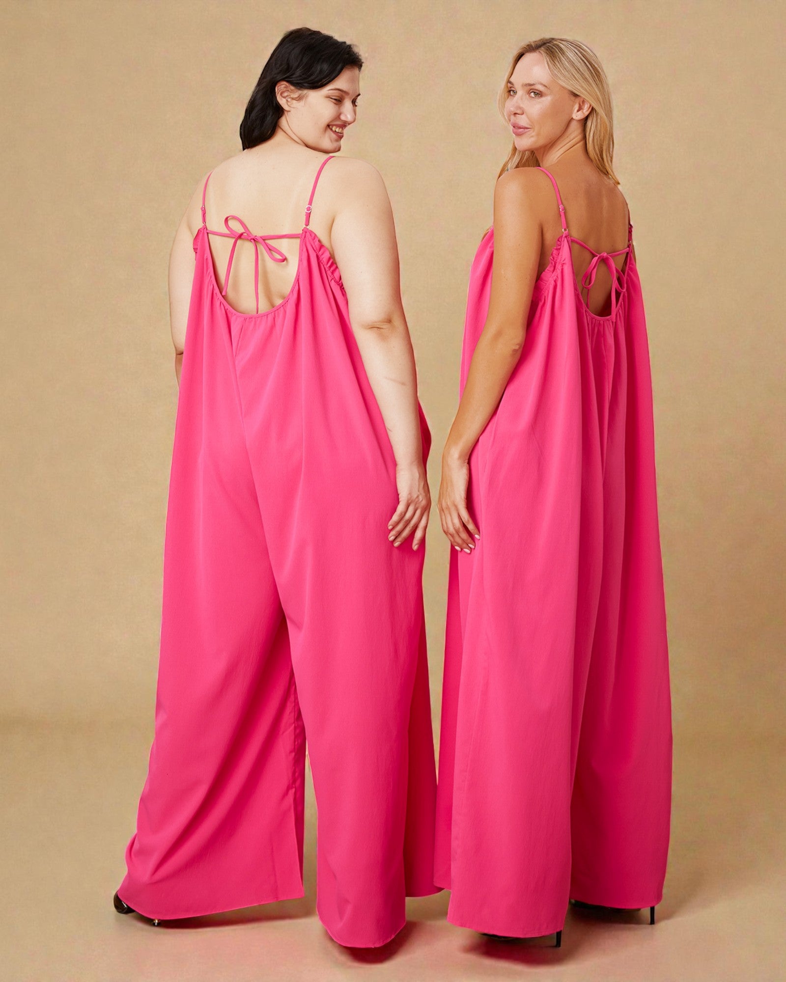 Two women wearing pink slip dresses against a beige background