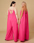 Two women wearing pink slip dresses against a beige background