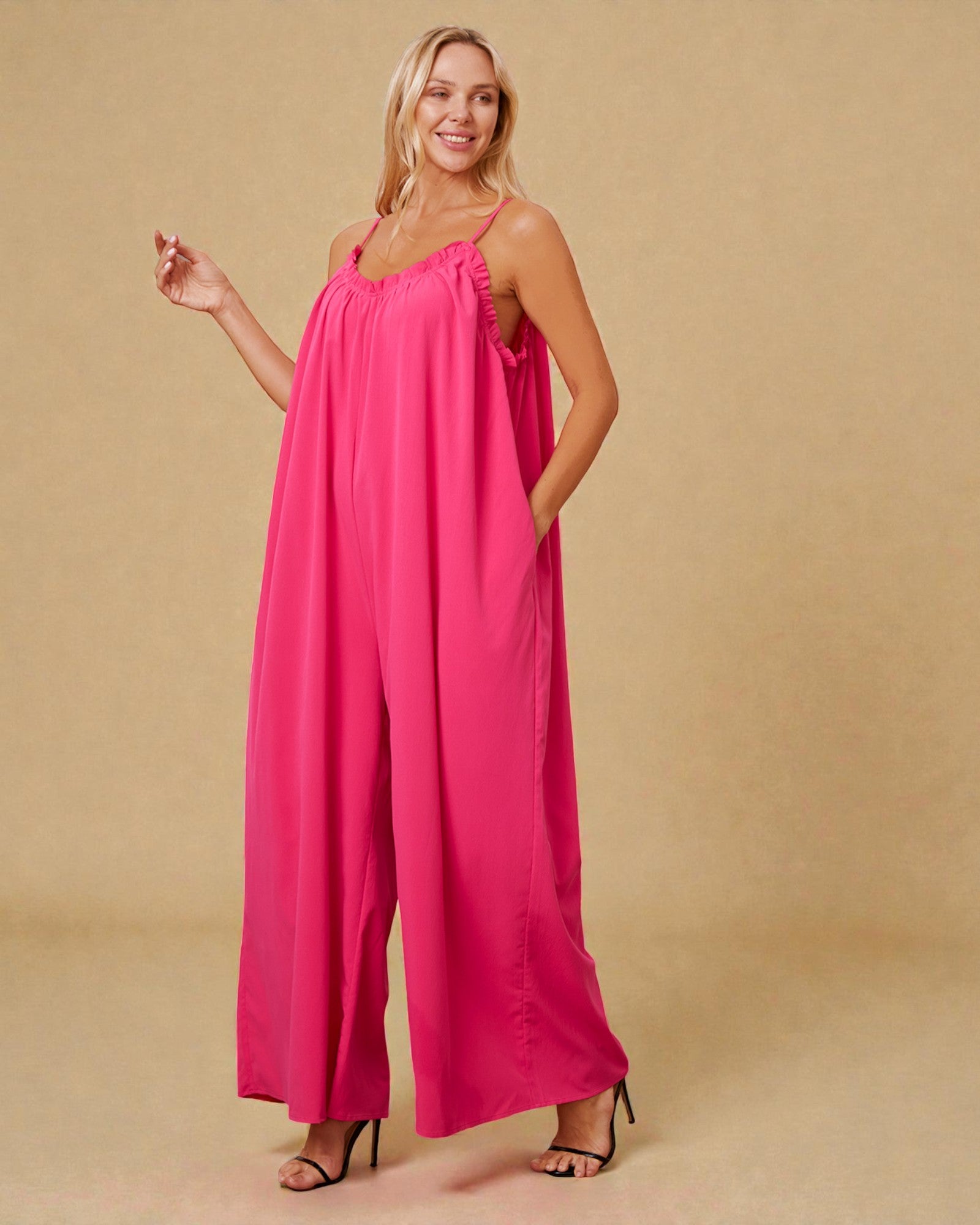 Woman wearing a bright pink jumpsuit on a beige background