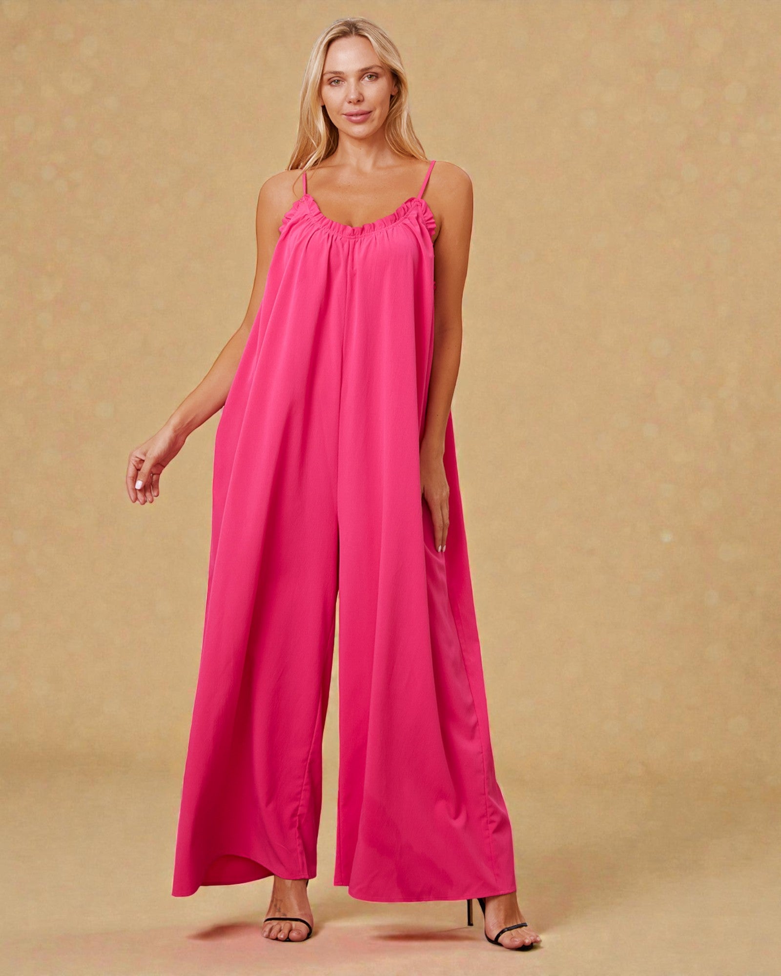 Woman wearing a pink jumpsuit against a beige background