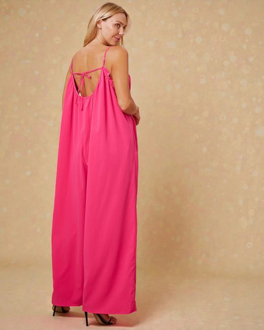 Woman wearing a pink dress with thin straps on a beige background