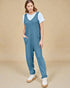 Woman wearing a blue jumpsuit over a white shirt on a beige background