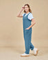 Woman wearing a blue jumpsuit and white sneakers on a beige background