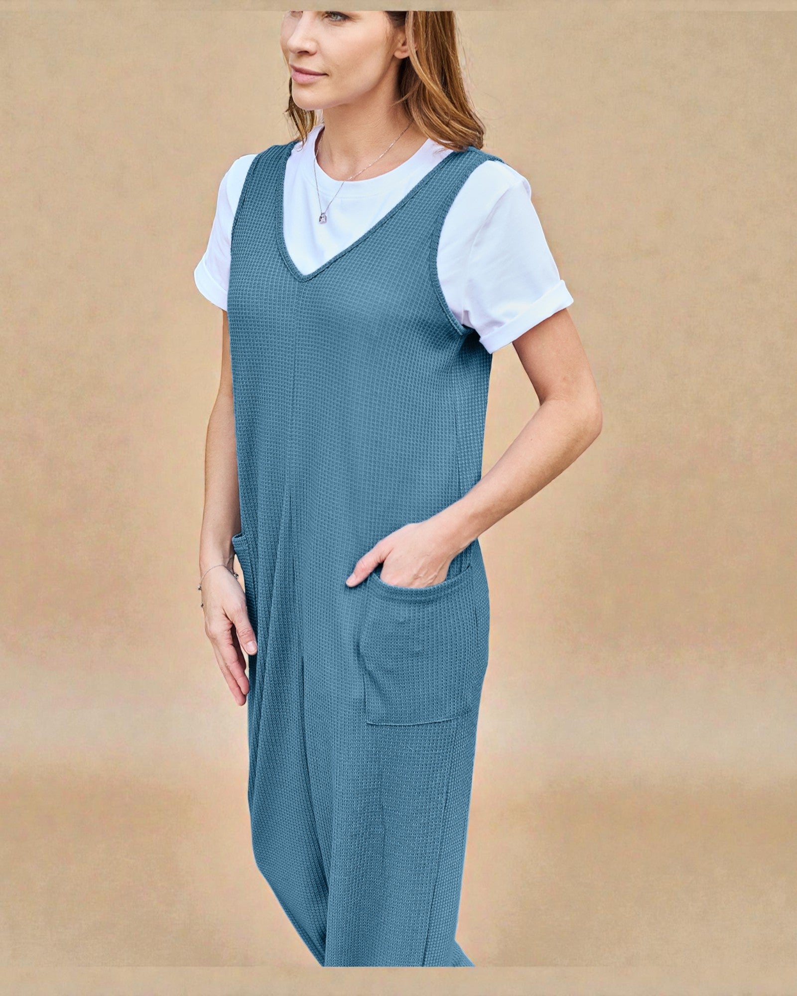Woman wearing a blue dress over a white shirt against a beige background