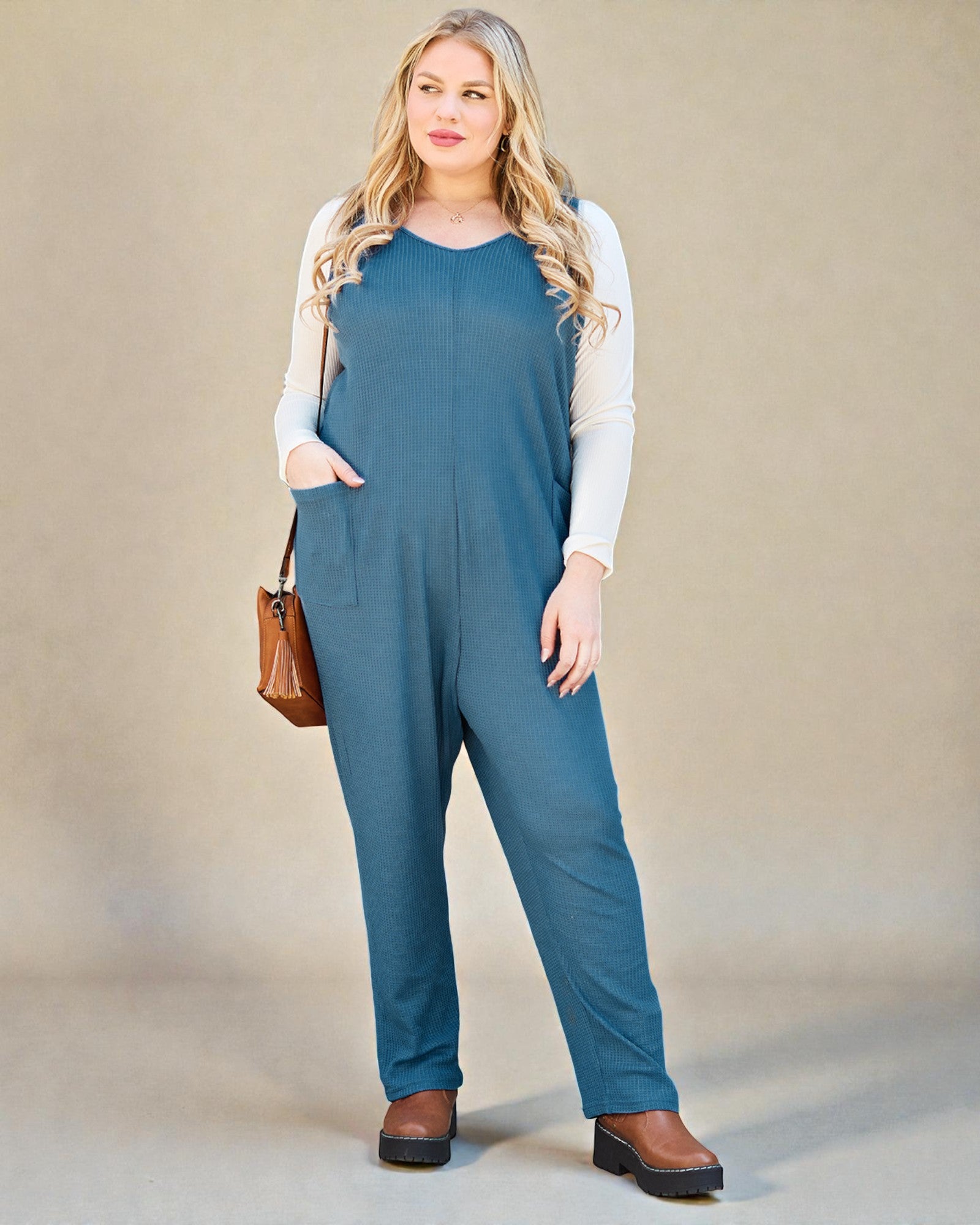 Woman wearing a blue jumpsuit with a beige background