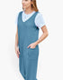 A woman wearing a slate blue ribbed knit overall dress over a white short-sleeve t-shirt, shown from the waist up against a plain white background.