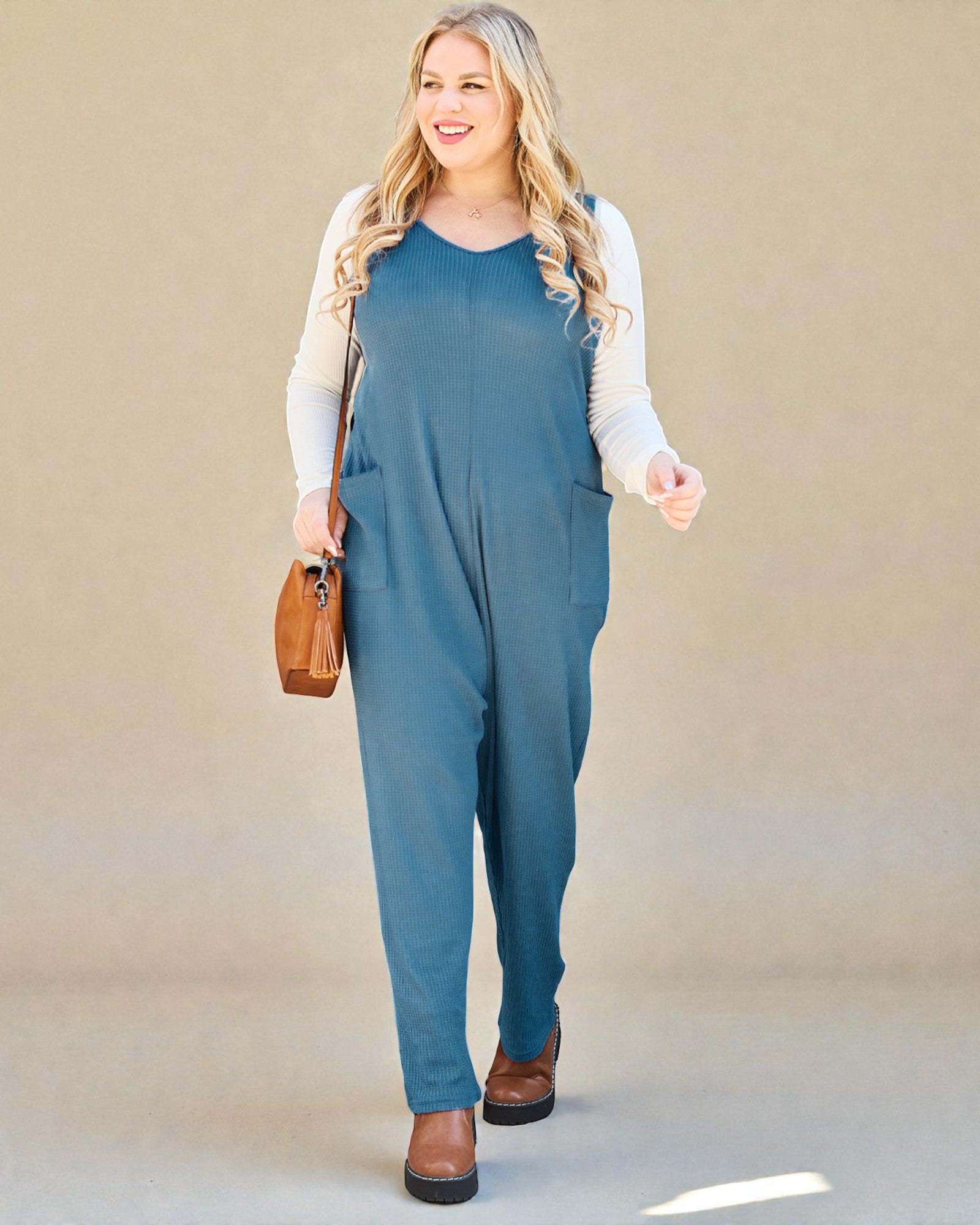 Woman wearing a blue jumpsuit with a beige background
