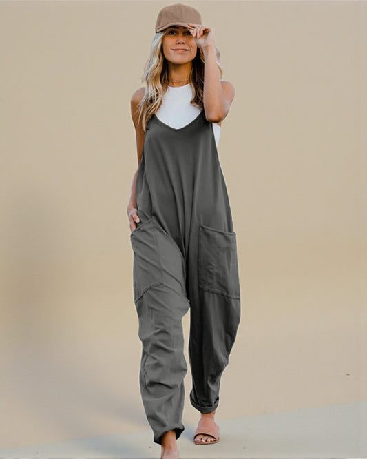 Woman wearing a gray jumpsuit and white top against a beige background