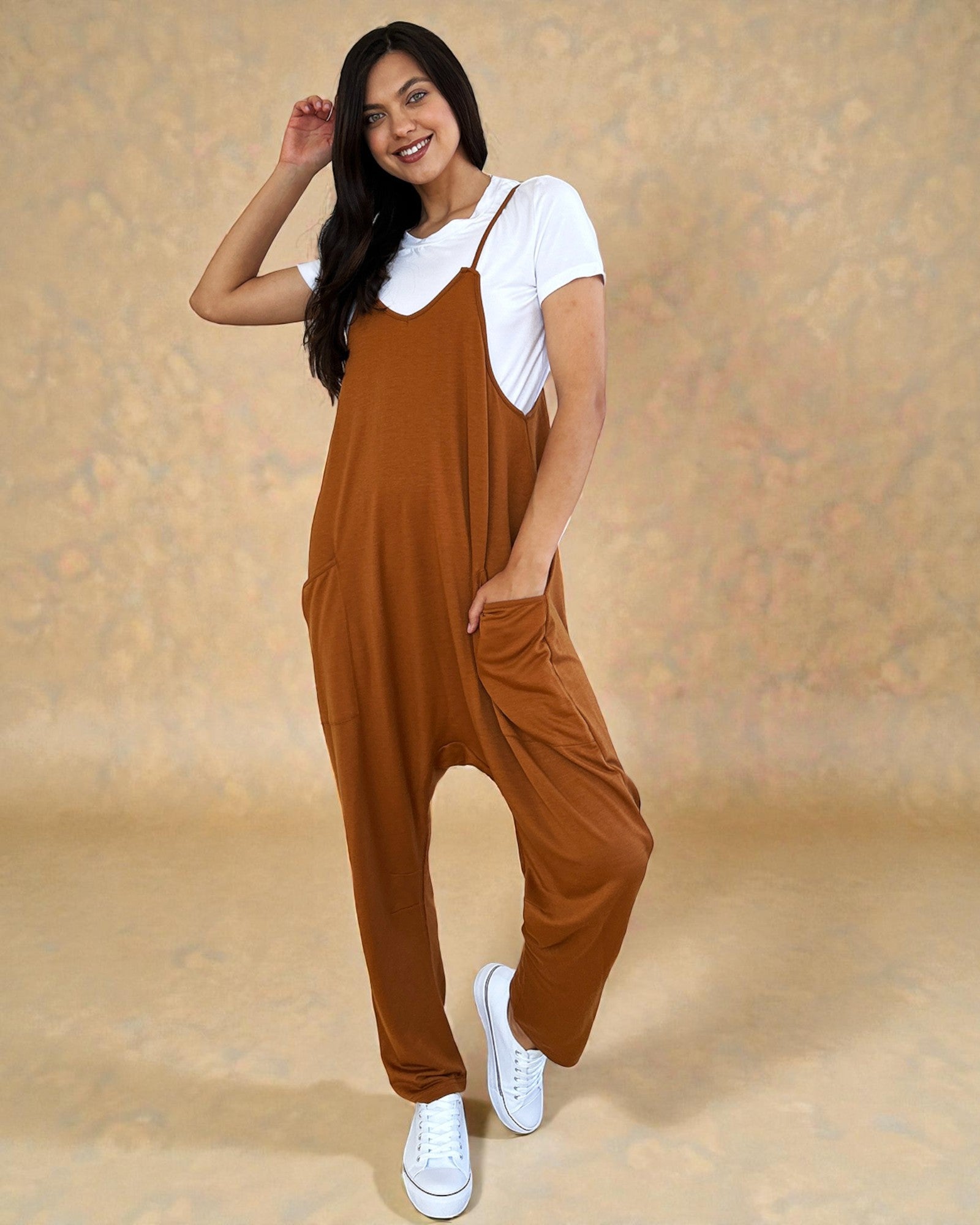 Woman wearing a brown jumpsuit over a white shirt on a beige background