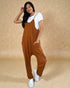 Woman wearing a brown jumpsuit over a white shirt on a beige background