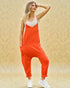 Woman wearing an orange jumpsuit with a white top against a beige background