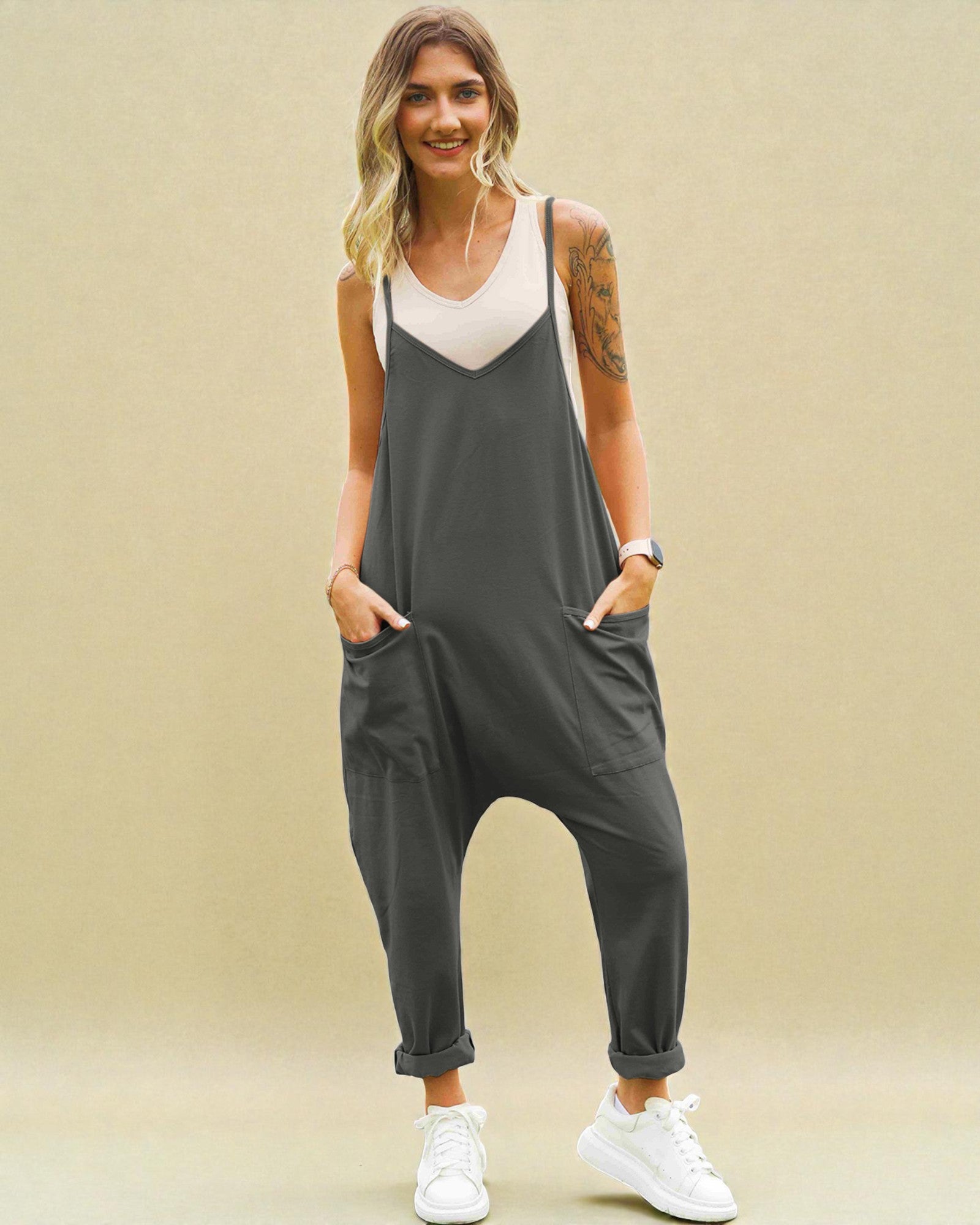 Woman wearing a gray jumpsuit with a beige background