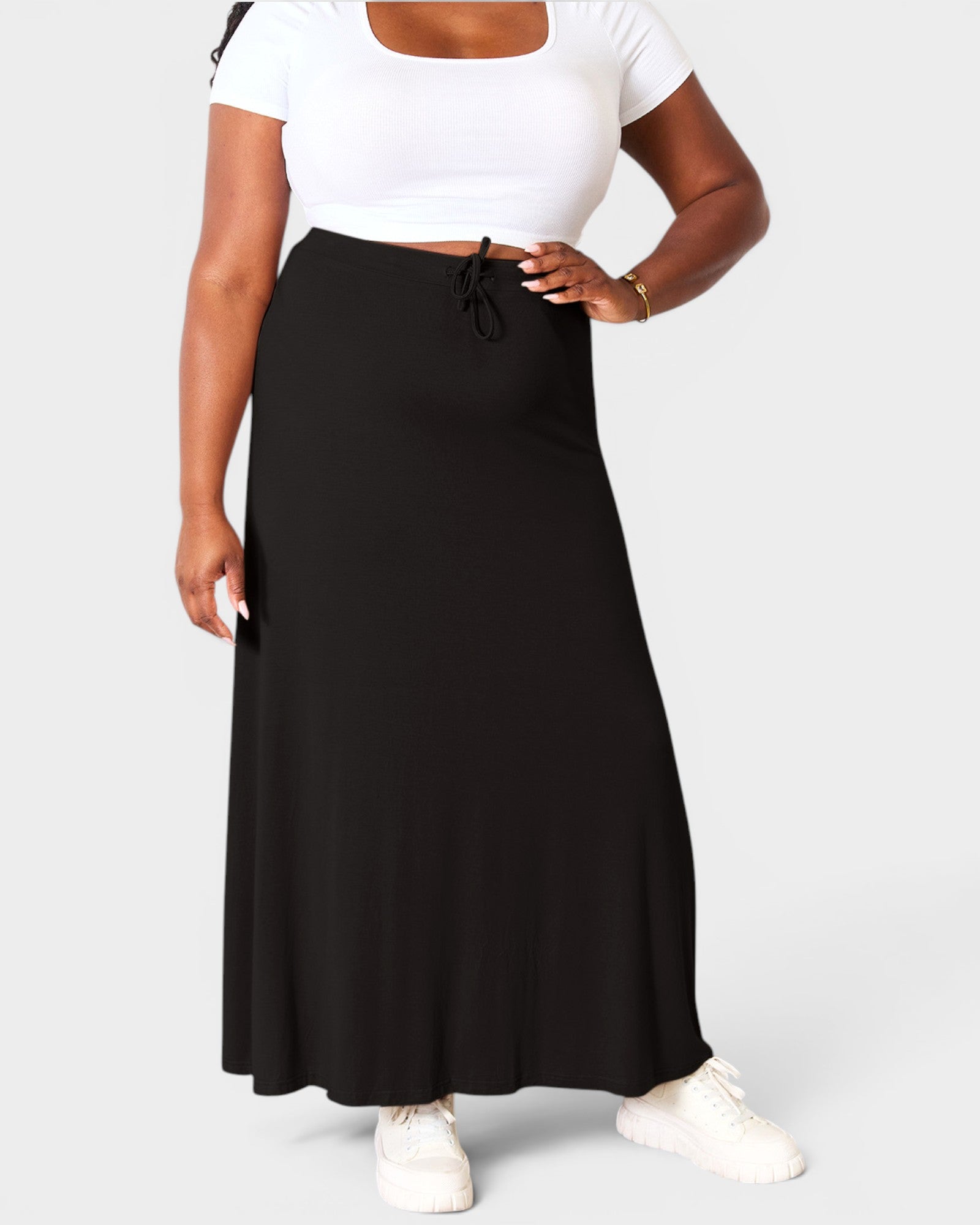 Person wearing a black skirt and white top on a plain background