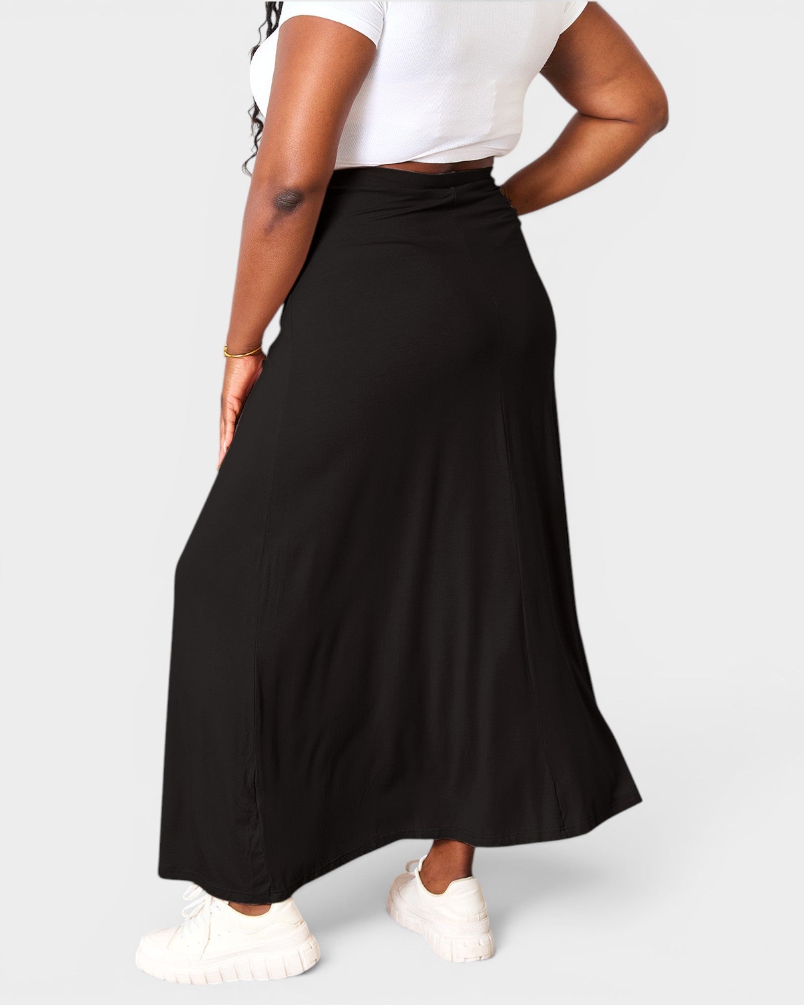 Person wearing a black skirt and white top on a plain background