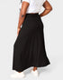 Person wearing a black skirt and white top on a plain background