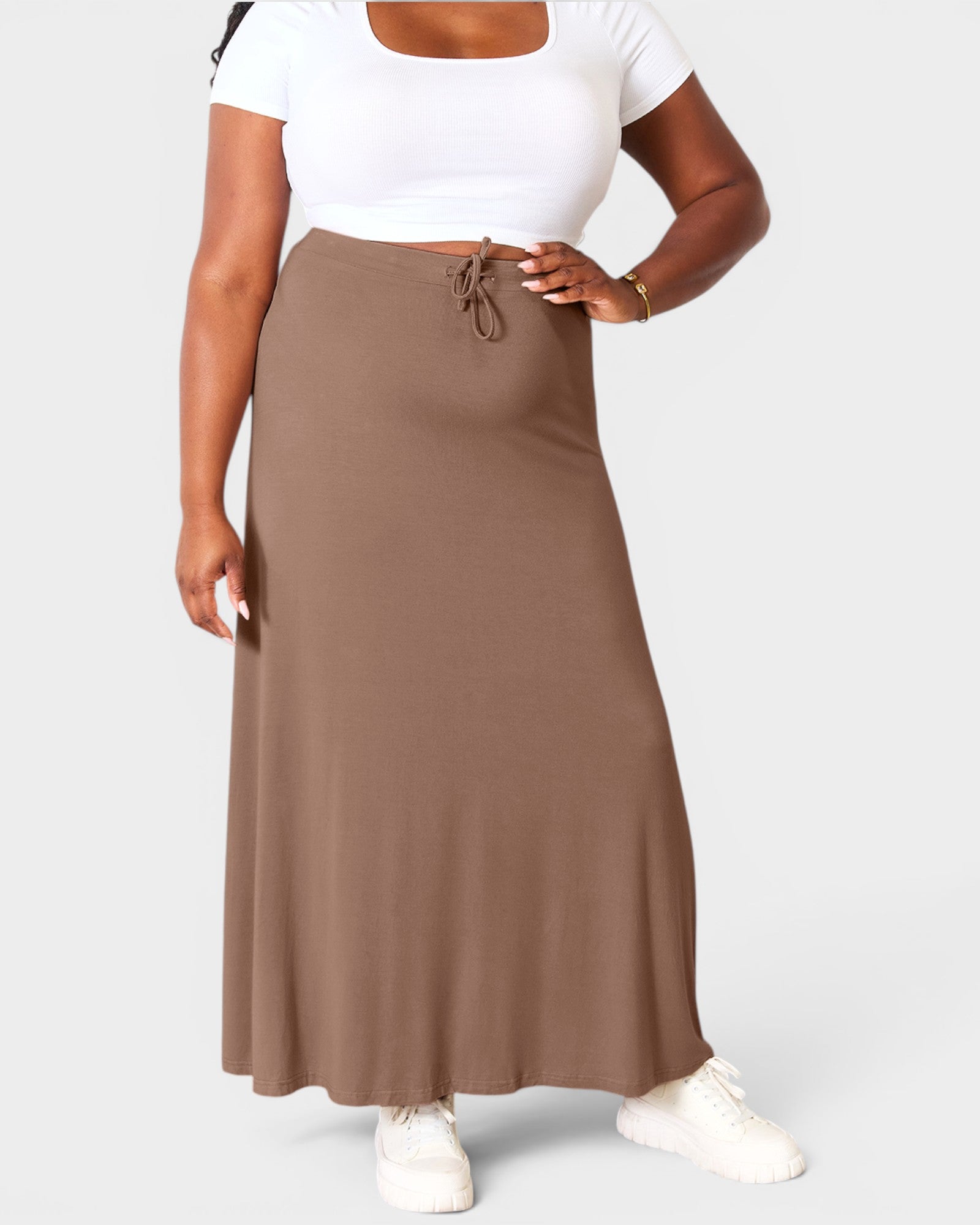 Person wearing a white top and brown skirt on a light gray background