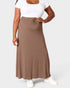 Person wearing a white top and brown skirt on a light gray background