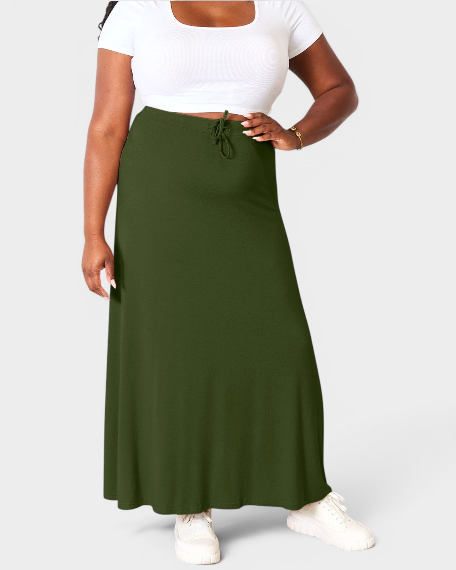 Person wearing a green skirt and white top on a plain background