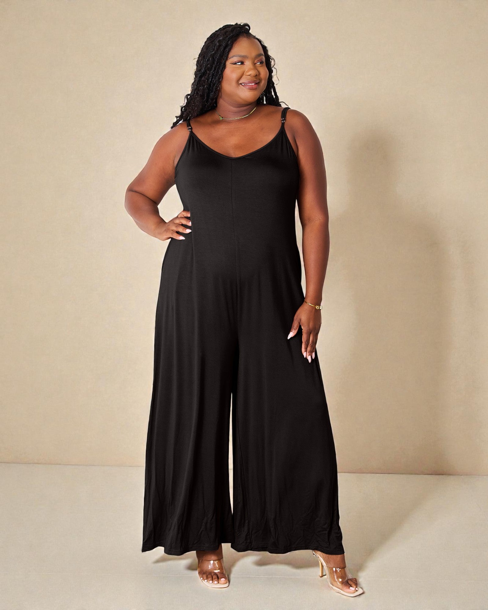 Woman wearing a black jumpsuit against a beige background