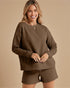 Woman wearing a brown textured sweater and shorts set on a beige background