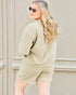 Woman wearing a beige outfit with sunglasses against a neutral background