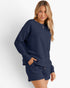 A woman modeling a matching navy blue textured lounge set consisting of a long-sleeve crewneck sweatshirt and shorts, against a clean white studio background.