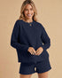 Woman wearing a navy blue outfit with a matching top and shorts on a beige background
