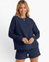 A woman modeling a matching navy blue lounge set featuring a textured knit long-sleeve top and shorts, set against a plain white studio background.