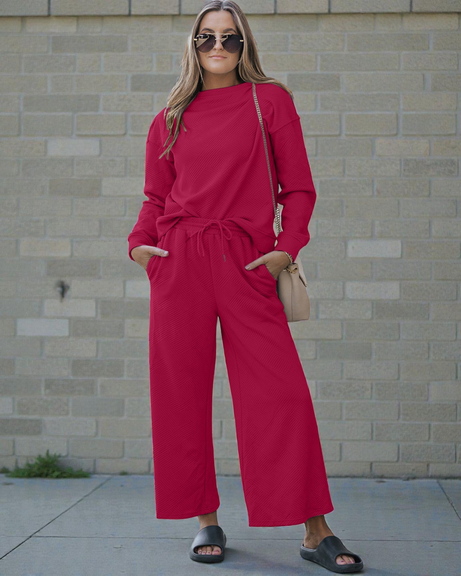 Woman wearing a red outfit standing against a brick wall.