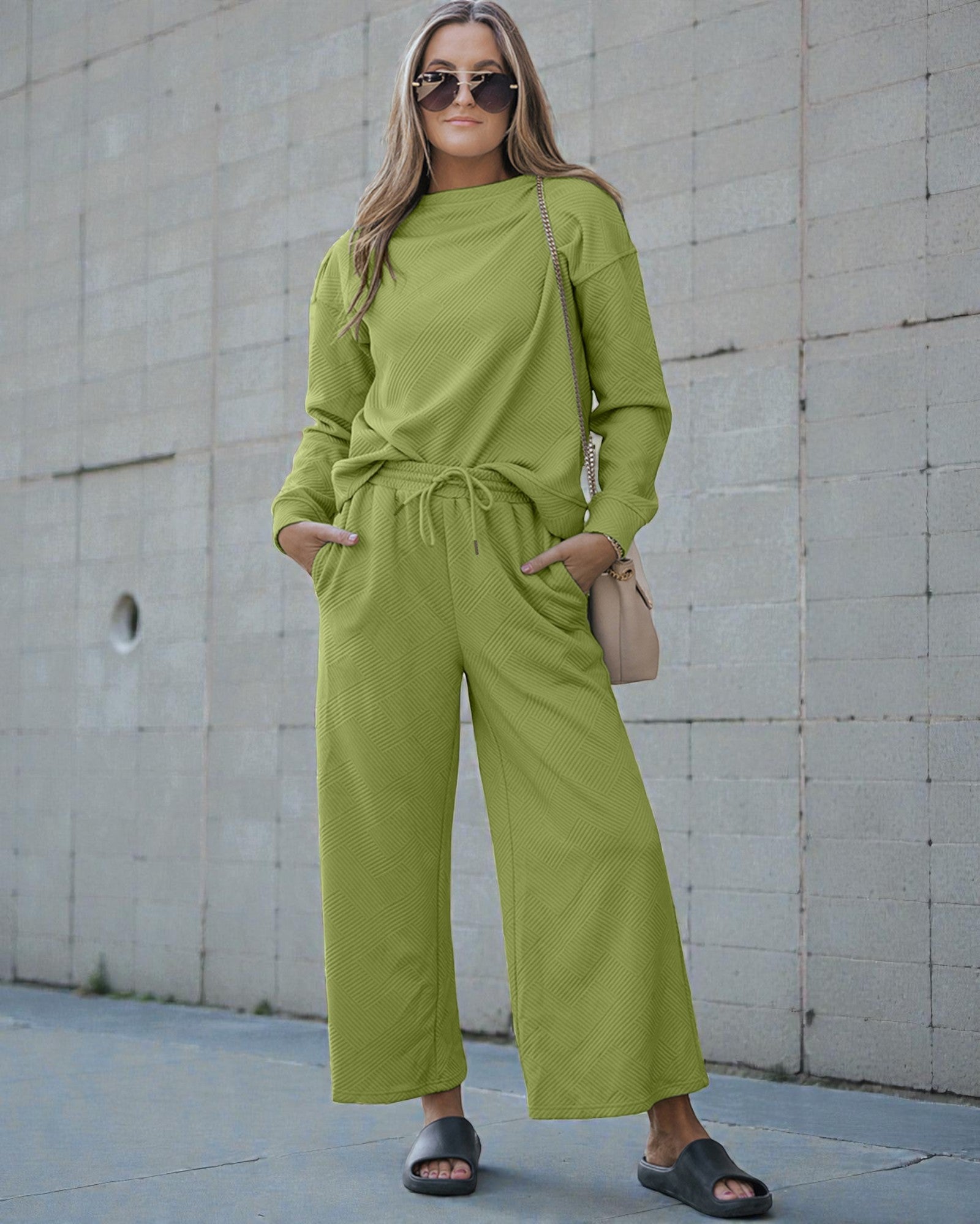 Woman wearing a green outfit standing against a concrete wall.