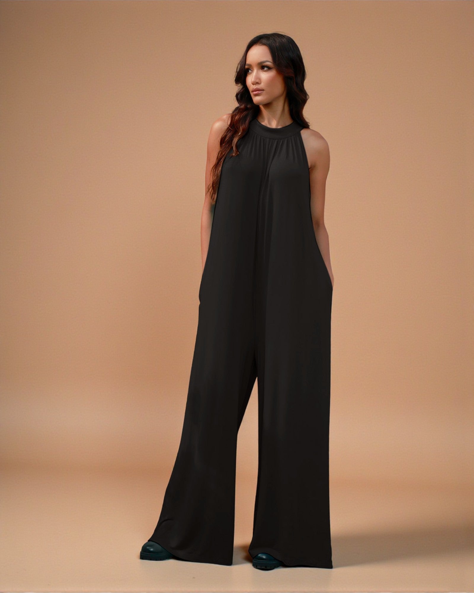 Woman wearing a black jumpsuit against a beige background
