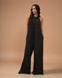 Woman wearing a black jumpsuit against a beige background