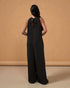 Woman wearing a black jumpsuit against a beige background