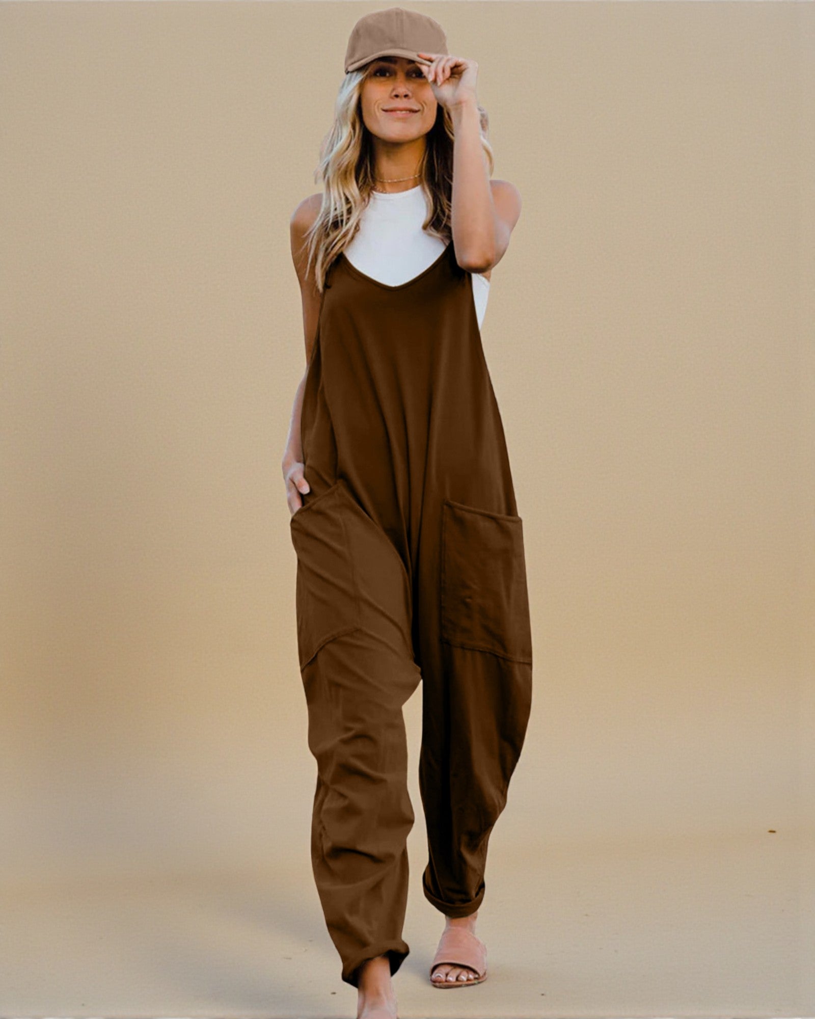Woman wearing a brown jumpsuit and beige cap against a beige background