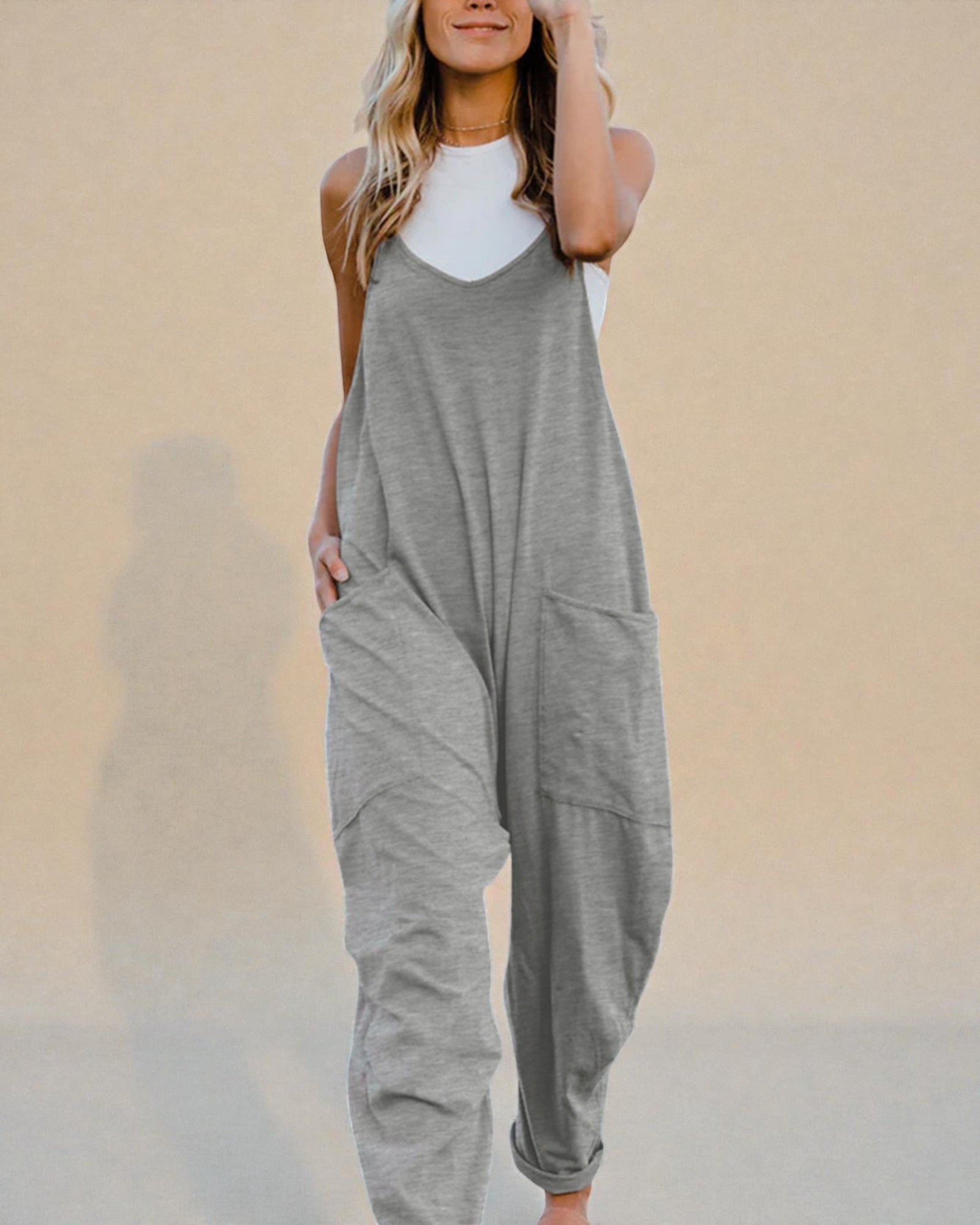 Woman wearing a gray jumpsuit against a beige background