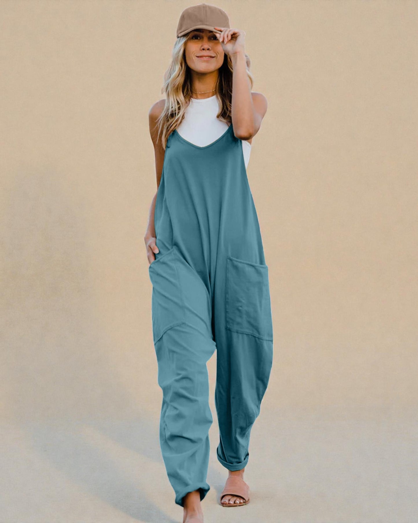 Woman wearing a teal jumpsuit against a beige background