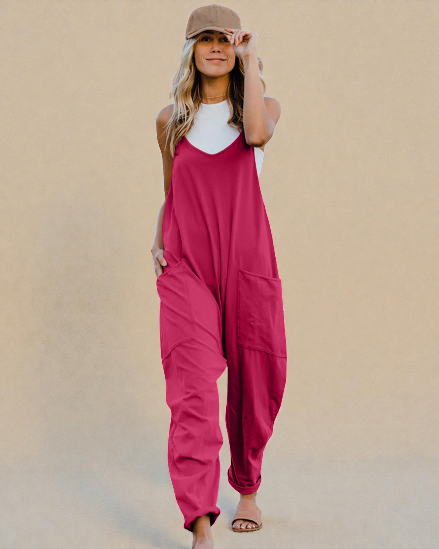 Woman wearing a pink jumpsuit and white top against a beige background