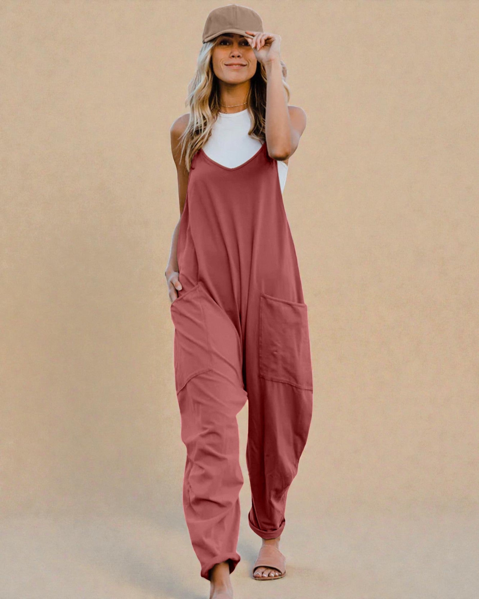 Woman wearing a pink jumpsuit against a beige background