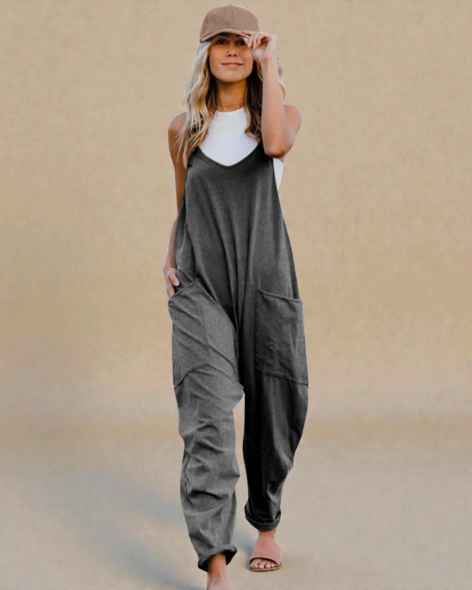 Woman wearing a gray jumpsuit and white top against a beige background