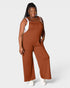 Woman wearing a brown ribbed jumpsuit on a white background