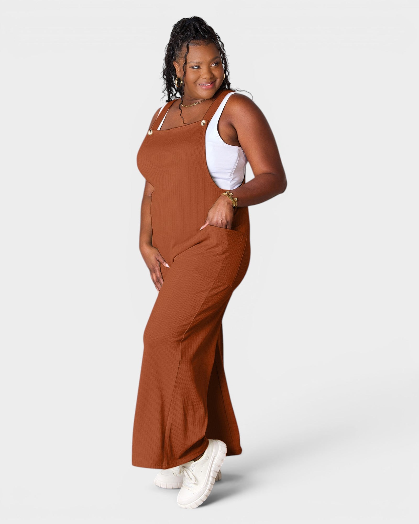 Woman wearing a brown dress over a white tank top on a white background