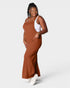 Woman wearing a brown dress over a white tank top on a white background