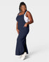 Woman wearing a navy blue dress over a white tank top on a white background