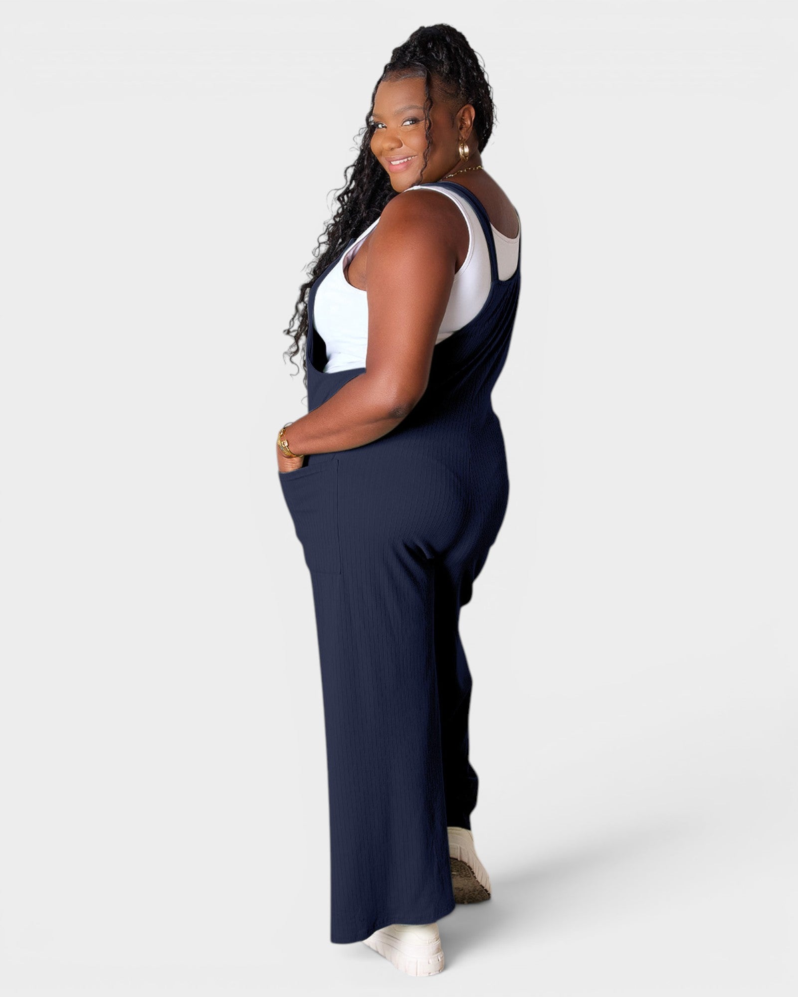 Woman wearing navy blue overalls on a white background
